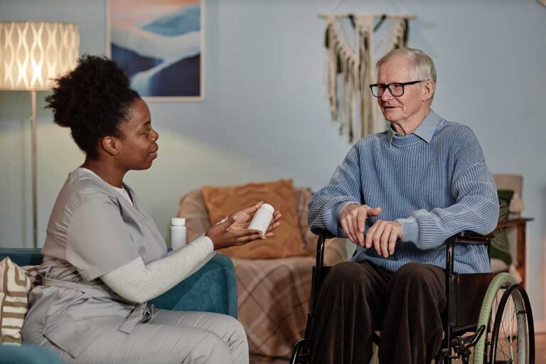 A social worker talking with an elderly resident at a table in a comfortable, bright common room.